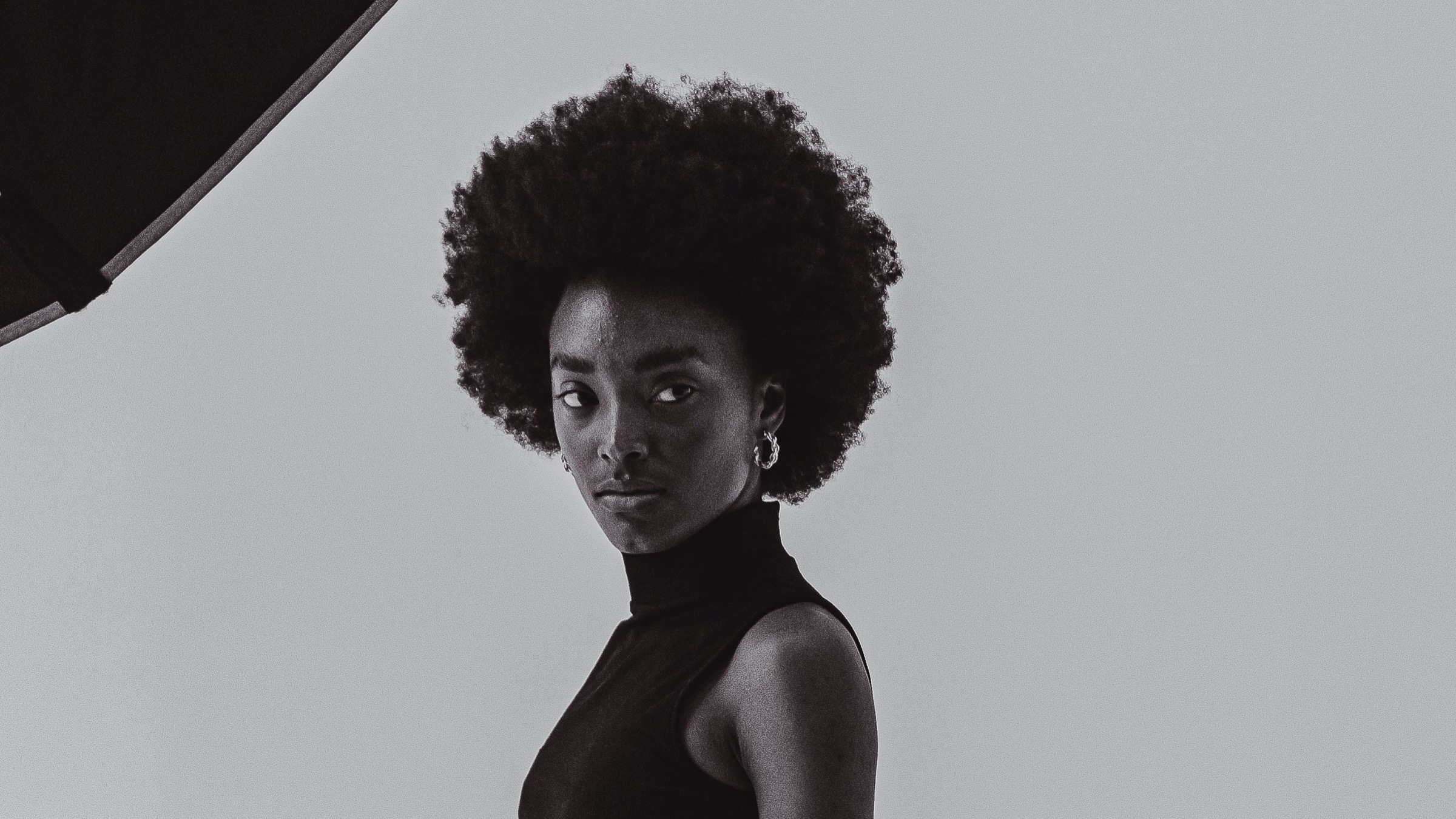 A model in a black turtleneck looks over her shoulder in the studio
